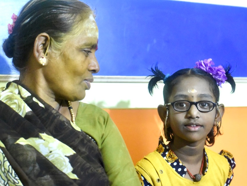 Young girl wearing her new glasses alongside her grandmother after treatment.
