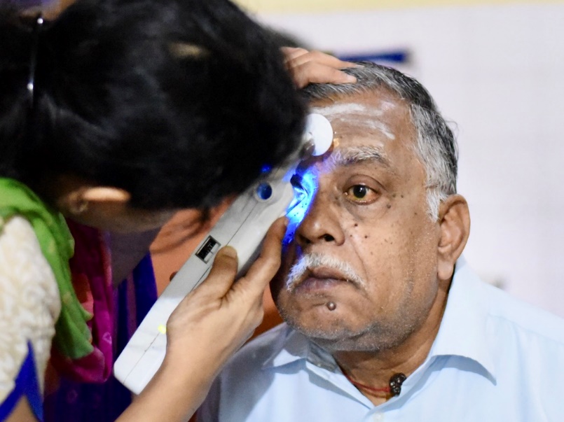 Doctor performing glaucoma pressure check on patient at an eye camp.