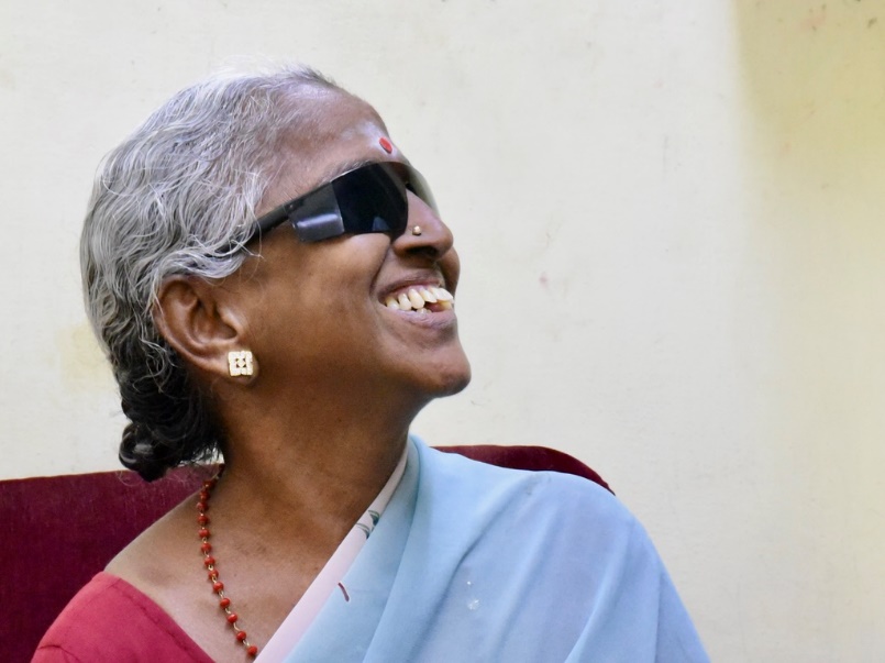 Elderly woman laughing joyfully after receiving her vision back post-surgery.